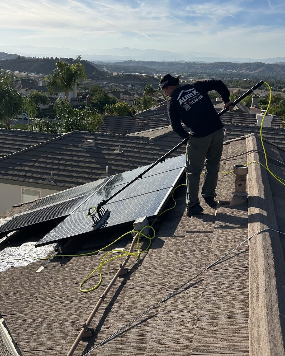 Solar array being soft-washed with a water-fed pole